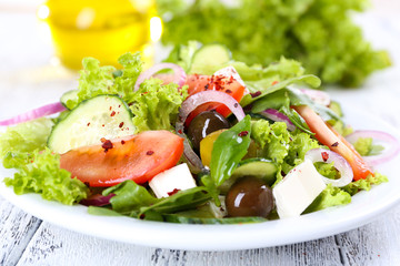 Greek salad in plate on color wooden table background