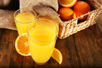 Glass of orange juice with slices and wicker basket with burlap