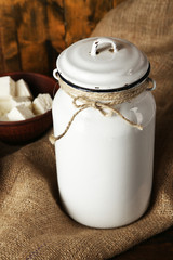 Milk can with cottage cheese on rustic wooden background