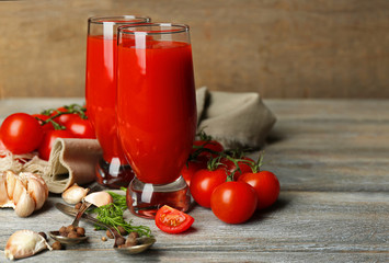Glasses of tasty tomato juice and fresh tomatoes on wooden