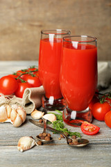 Glasses of tasty tomato juice and fresh tomatoes on wooden