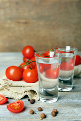 Glasses of ouzo and tomatoes on wooden table