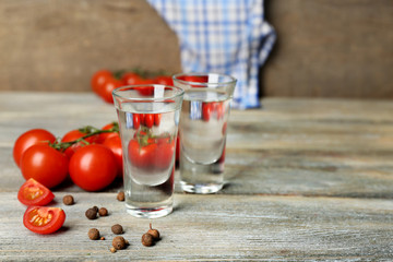 Glasses of ouzo and tomatoes on wooden table
