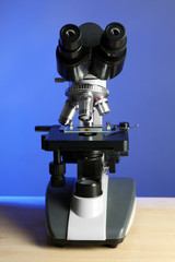Microscope on table, on blue background