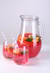 Pink lemonade in glasses and pitcher isolated on white
