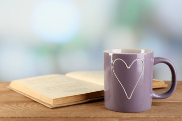 Cup of tea and book on table, on bright background