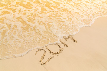 Year 2014 number written on sandy beach