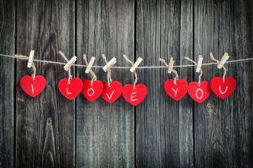 Red hearts on line over a old wooden boards background