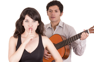 beautiful girl gesturing silence while young man serenades her