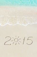 inscription 2015 on sea beach with sun rays against wave foam
