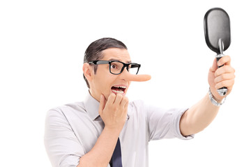 Scared man with long nose looking in a mirror