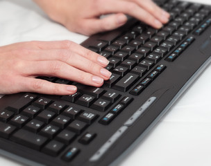 Female office worker typing on a black keyboard