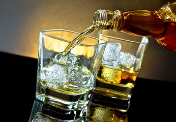 barman pouring whiskey in front of whiskey glass on warm light