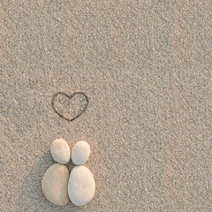Fototapeta na wymiar Pebbles shapes lovers with heart on the sand