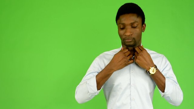 black man adjusts clothing, smiles - green screen