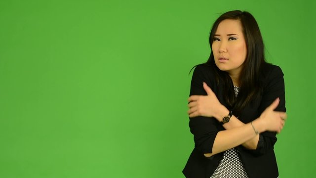 asian woman shivers - cold - green screen studio
