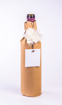 bottle wrapped in paper with white flower and blank card