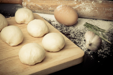 dough on a board with flour. olive oil, eggs, rolling pin, garli