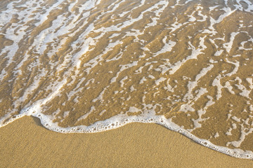 Fototapeta na wymiar Sand on a sea beach, with a soft wave.