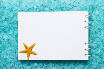 Fototapeta na wymiar notepad and starfish on bath salt background