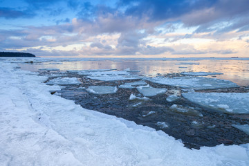 Winter coastal landscape with ice fragments on still water