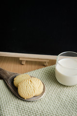 Cokkies in Wood ladle and glass of milk with black board