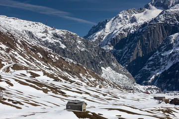 Alpine mountain landscape with cottage, snow is melting away