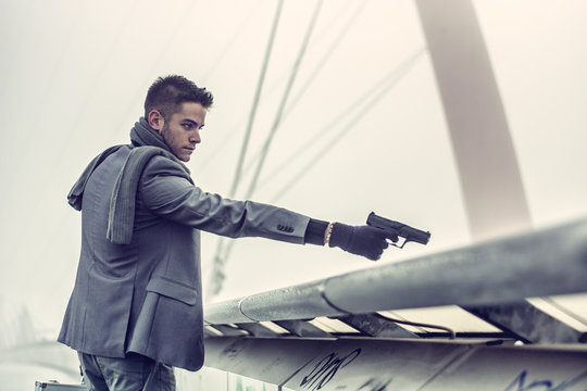 Young detective or policeman or mobster firing a gun