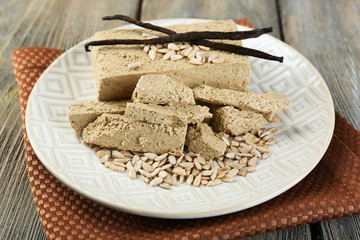 Sunflower halva on plate, on wooden background