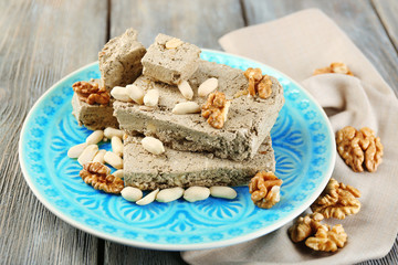 Sunflower halva with nuts on plate, on wooden background