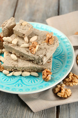 Sunflower halva with nuts on plate, on wooden background