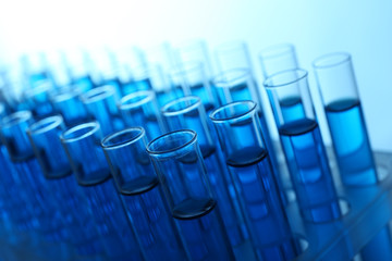 Obraz premium Blue water in a transparent test-tube on light background