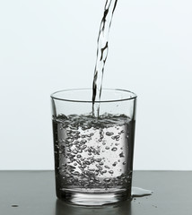 Pouring water from bottle on  glass isolated on white