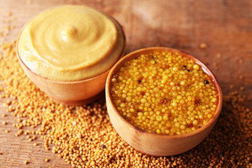 Mustard in bowls on wooden background
