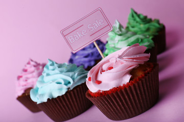 Delicious cupcakes with inscription on color background