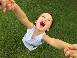 Young mixed-race child being spun around at the park.