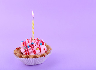 Cake with birthday candle on purple background