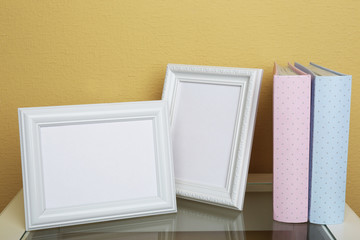 Photo frames with albums on coffee table on wallpaper