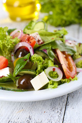 Greek salad in plate on color wooden table background