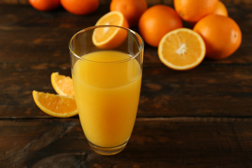 Glass of orange juice with slices on wooden table background
