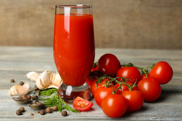 Glass of tasty tomato juice and fresh tomatoes on wooden table