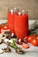 Glasses of tasty tomato juice and fresh tomatoes on wooden