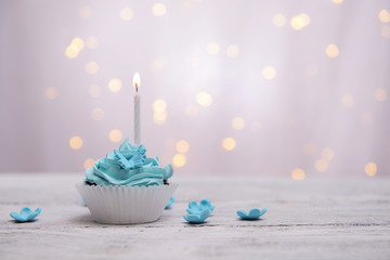 Delicious birthday cupcake on table on light background