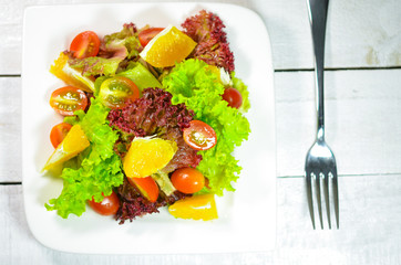 Disk of salad on wooden white table