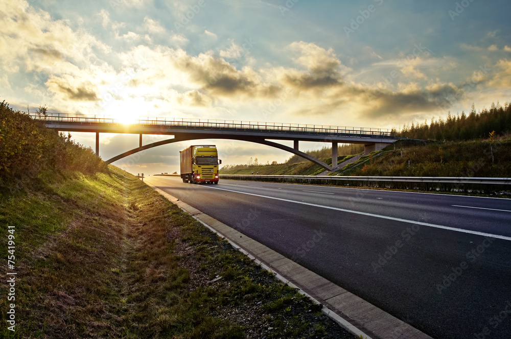 Poster sunset over highway, bridge and riding a yellow truck