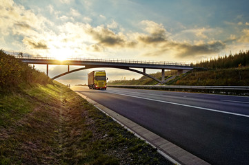 Sunset over highway, bridge and riding a yellow truck