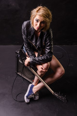 Beautiful blonde dressed in leather jacket with electric guitar