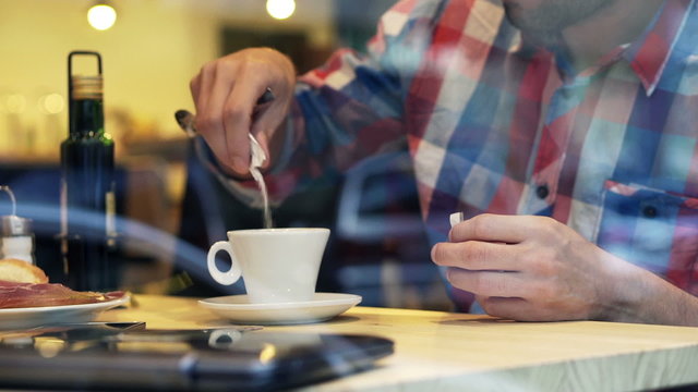 Man hands adding sugar into tea in cafe