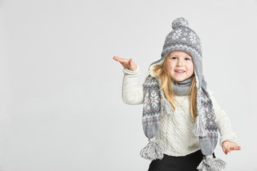 Beautiful blond girl playing in the winter warm hat and scarf on