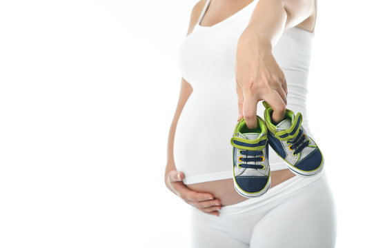 Pregnant woman showing small shoes for the unborn baby